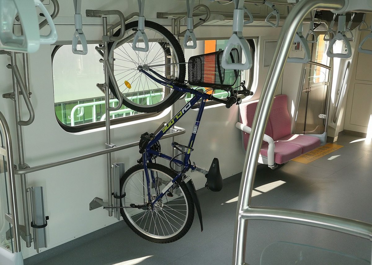 一台自行車以立式固定在電聯車車廂內的自行車架上