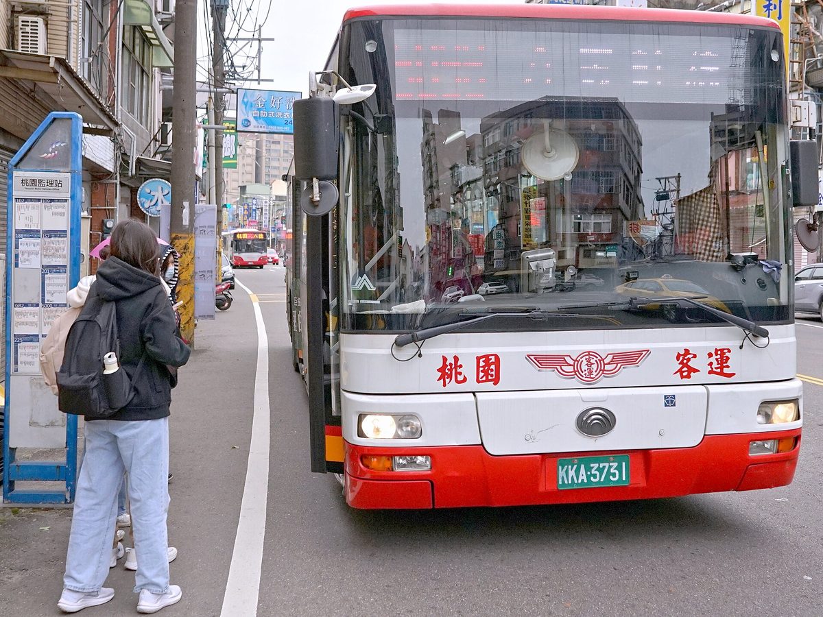 桃園客運公車停靠站牌，一名背背包的乘客在站牌旁等候