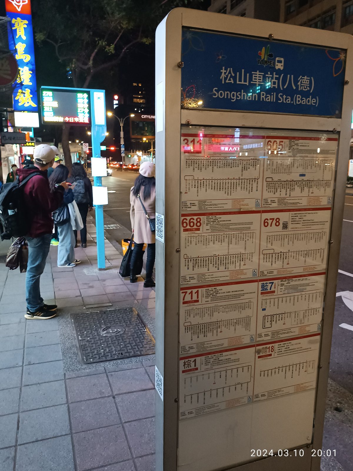 台北松山車站八德路口的聯營公車站牌，一整排密集的路線牌在夜間亮著