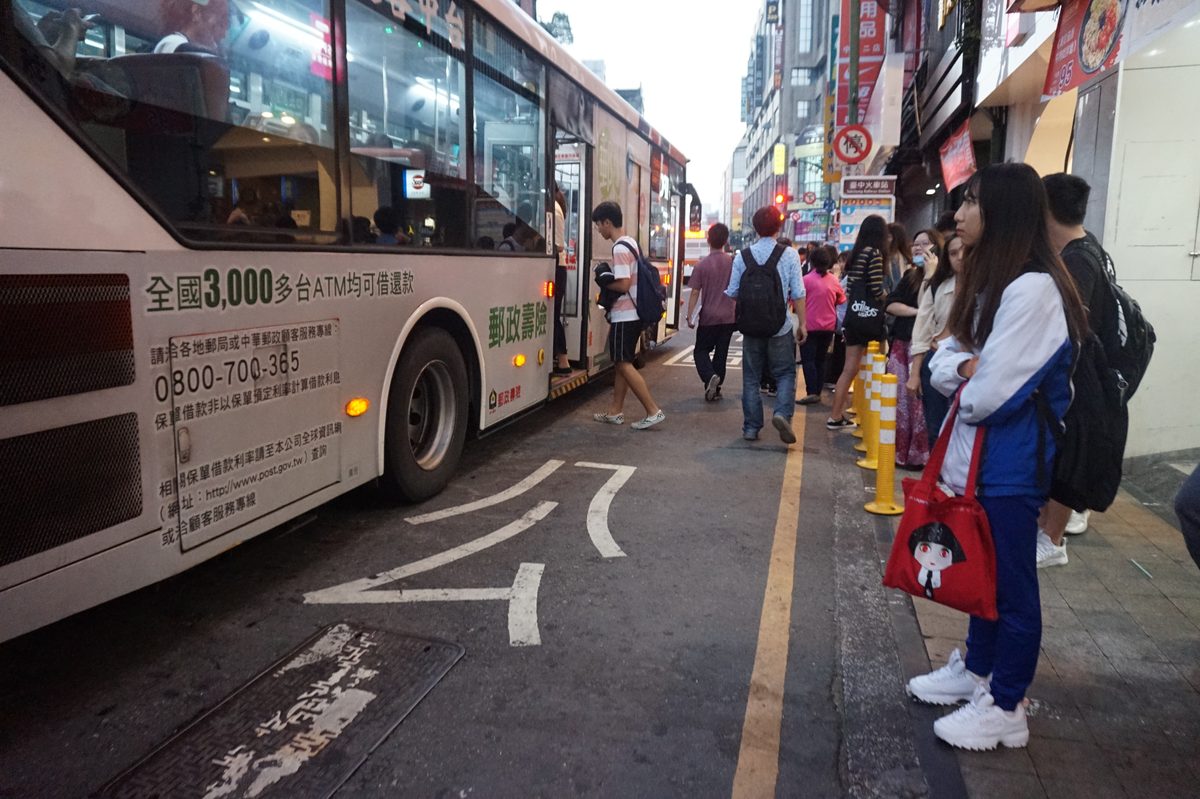 台中臺灣大道公車站牌旁，公車靠站、多名乘客在人行道等車與上車