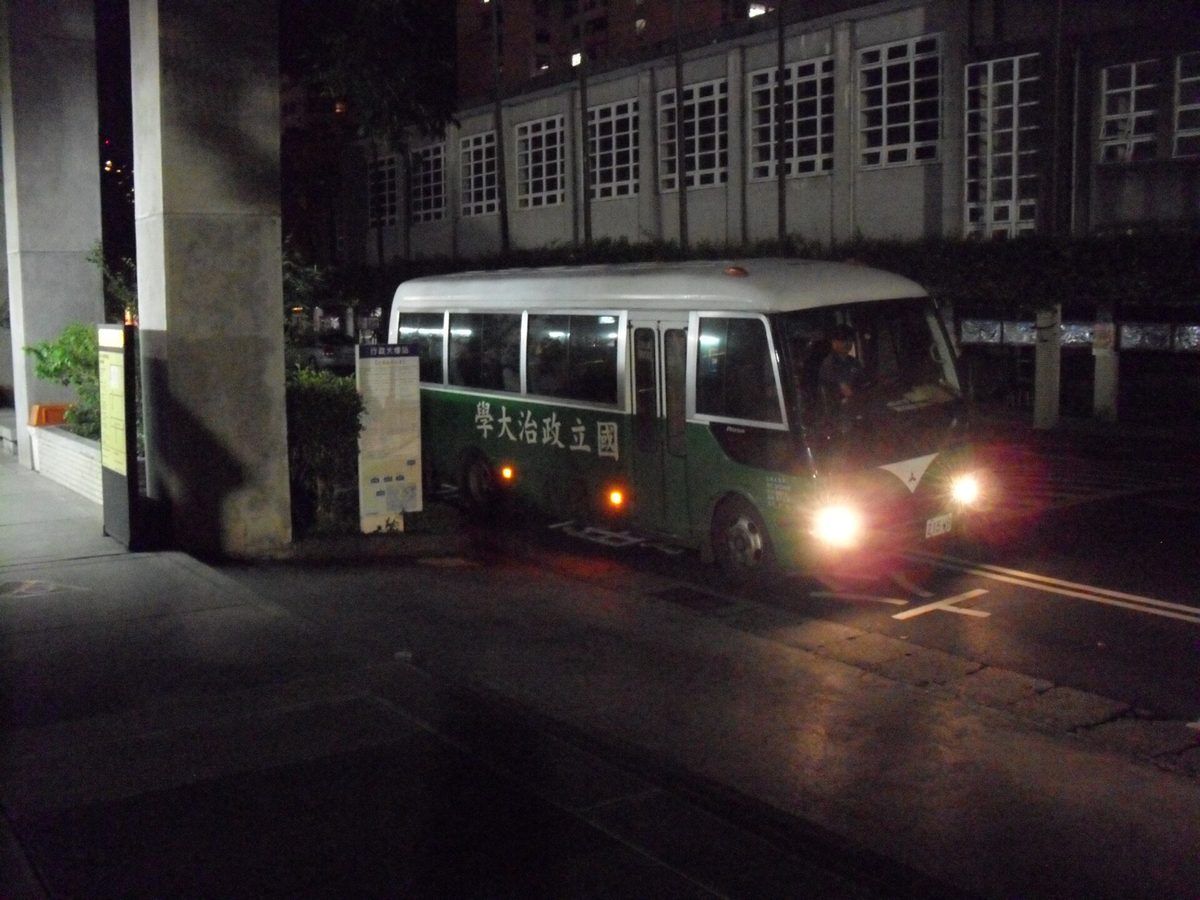 夜間校園門口一輛公車亮著車燈駛出
