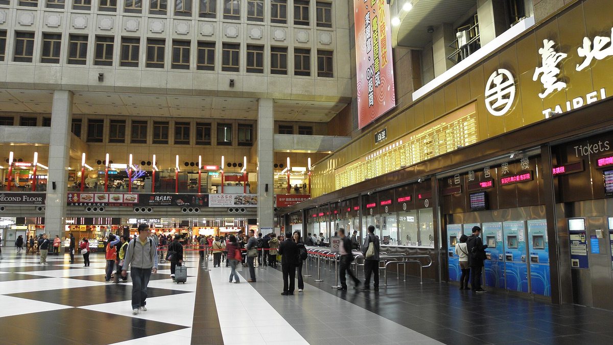台北車站大廳，旅客往來於商店與售票區之間