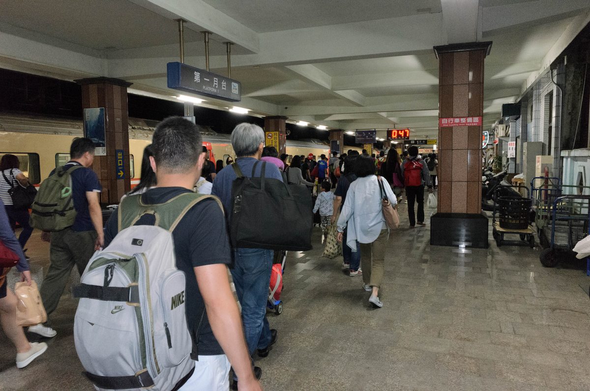 台鐵花蓮車站第一月台，深夜列車進站後旅客提著行李往出口走，月台時鐘顯示零時四十七分
